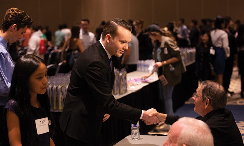 Cal State Student Brian Ruef shakes hands with event attendee